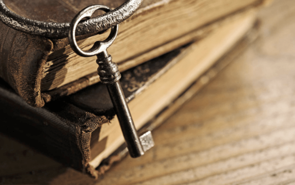 An old iron key resting on a stack of aged, well-worn books, symbolising the ancient teachings unlocked in these classes